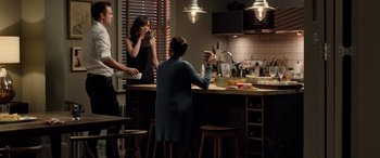 Movie still from “I Give It a Year” (2013), directed by Dan Mazer – A group of people standing around a kitchen counter; Wide shot, Over the shoulder angle