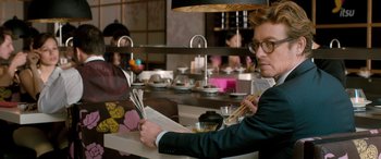 Movie still from “I Give It a Year” (2013), directed by Dan Mazer – A man sitting at a table reading a newspaper; Close Up shot, Over the shoulder angle