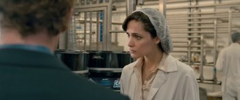 Movie still from “I Give It a Year” (2013), directed by Dan Mazer – A woman wearing a head covering in an industrial setting; Close Up shot, Over the shoulder angle