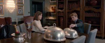 Movie still from “I Give It a Year” (2013), directed by Dan Mazer – A woman and a man sitting at a table with a dome on top of it; Medium shot, High angle