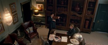 Movie still from “I Give It a Year” (2013), directed by Dan Mazer – Three people are sitting at a table in a room; Wide shot, High angle