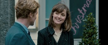 Movie still from “I Give It a Year” (2013), directed by Dan Mazer – A woman in a black coat smiling at a man in a black suit; Close Up shot, Over the shoulder angle