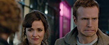 Movie still from “I Give It a Year” (2013), directed by Dan Mazer – A woman standing next to a man in front of a building; Close Up shot, Over the shoulder angle