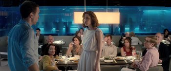 Movie still from “I Give It a Year” (2013), directed by Dan Mazer – A woman standing in front of a group of diners; Medium shot, Over the shoulder angle