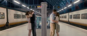 Movie still from “I Give It a Year” (2013), directed by Dan Mazer – A group of young people kissing in a train station; Wide shot, Low angle