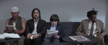 Movie still from “I Heart Huckabees” (2004), directed by David O. Russell – A man and a boy are sitting on a couch; Medium shot, Low angle