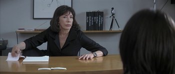Movie still from “I Heart Huckabees” (2004), directed by David O. Russell – A woman sitting at a table in front of another woman; Medium shot, Over the shoulder angle