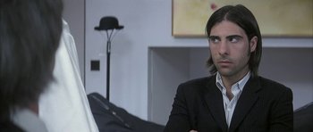 Movie still from “I Heart Huckabees” (2004), directed by David O. Russell – A man in a suit sitting in front of a laptop; Close Up shot, Over the shoulder angle