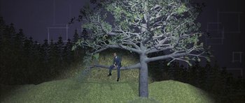 Movie still from “I Heart Huckabees” (2004), directed by David O. Russell – A man in a suit sitting on a tree branch; Wide shot, High angle