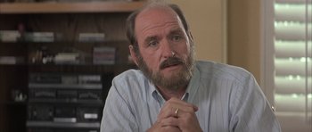 Movie still from “I Heart Huckabees” (2004), directed by David O. Russell – An older man with a beard is sitting in a room; Close Up shot, Low angle