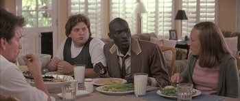 Movie still from “I Heart Huckabees” (2004), directed by David O. Russell – A man sitting at a table with a plate of food in front of him; Medium shot, Over the shoulder angle