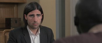 Movie still from “I Heart Huckabees” (2004), directed by David O. Russell – A man with long hair sitting at a table in front of a mirror; Close Up shot, Over the shoulder angle