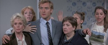 Movie still from “I Heart Huckabees” (2004), directed by David O. Russell – A man in a suit and tie standing next to an older woman; Close Up shot, Over the shoulder angle