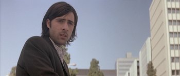 Movie still from “I Heart Huckabees” (2004), directed by David O. Russell – A person wearing a suit and tie; Close Up shot, Low angle