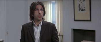 Movie still from “I Heart Huckabees” (2004), directed by David O. Russell – A man with long hair and a suit jacket on; Close Up shot, Over the shoulder angle