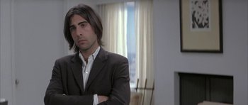 Movie still from “I Heart Huckabees” (2004), directed by David O. Russell – A man in a black suit and a white shirt; Close Up shot, Over the shoulder angle