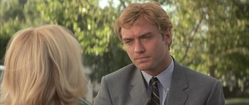 Movie still from “I Heart Huckabees” (2004), directed by David O. Russell – A man in a gray suit and a black tie; Close Up shot, Over the shoulder angle