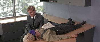Movie still from “I Heart Huckabees” (2004), directed by David O. Russell – A man in a business suit laying on the ground next to a woman; Medium shot, High angle