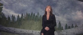 Movie still from “I Heart Huckabees” (2004), directed by David O. Russell – A woman in a black dress standing in front of trees; Medium shot, Low angle