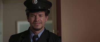 Movie still from “I Heart Huckabees” (2004), directed by David O. Russell – A person wearing a hat and a suit; Close Up shot, Over the shoulder angle