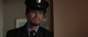 Movie still from “I Heart Huckabees” (2004), directed by David O. Russell – A person wearing a hat and a suit; Close Up shot, Over the shoulder angle