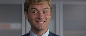 Movie still from “I Heart Huckabees” (2004), directed by David O. Russell – A person wearing a suit and smiling; Close Up shot, Low angle