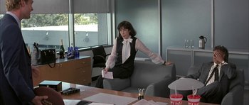 Movie still from “I Heart Huckabees” (2004), directed by David O. Russell – A woman sitting on top of a couch in a room; Medium shot, Over the shoulder angle