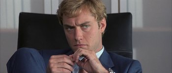Movie still from “I Heart Huckabees” (2004), directed by David O. Russell – A person wearing a suit and tying a necktie; Close Up shot, Over the shoulder angle