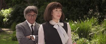 Movie still from “I Heart Huckabees” (2004), directed by David O. Russell – A man and a woman standing next to each other in front of flowers; Medium shot, Over the shoulder angle