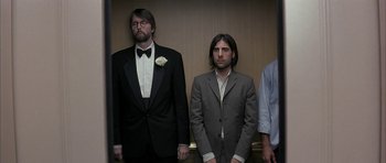 Movie still from “I Heart Huckabees” (2004), directed by David O. Russell – A group of men standing next to each other in a room; Medium shot, Low angle