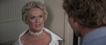 Movie still from “I Heart Huckabees” (2004), directed by David O. Russell – An older woman wearing a white shirt and pearl necklace; Close Up shot, Over the shoulder angle