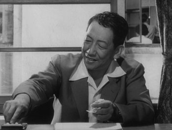 Movie still from “I Live in Fear” (1955), directed by Akira Kurosawa – An older man sitting at a table writing on a piece of paper; Close Up shot, Low angle
