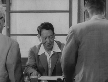 Movie still from “I Live in Fear” (1955), directed by Akira Kurosawa – A black - and - white photo of a man sitting at a table; Medium shot, Low angle