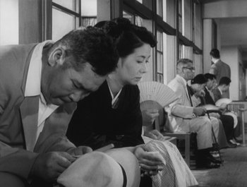 Movie still from “I Live in Fear” (1955), directed by Akira Kurosawa – A man and a woman sitting next to each other; Medium shot, Low angle