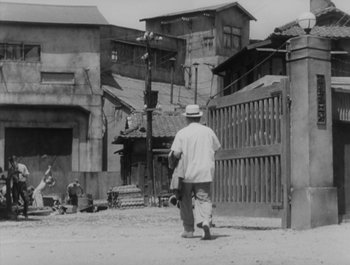 Movie still from “I Live in Fear” (1955), directed by Akira Kurosawa – An older man walking down the street with a hat on his head; Wide shot, High angle