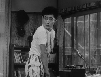 Movie still from “I Live in Fear” (1955), directed by Akira Kurosawa – A young man standing in front of a record player; Medium shot, Low angle