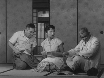 Movie still from “I Live in Fear” (1955), directed by Akira Kurosawa – A group of people sitting on the ground; Medium shot, Low angle