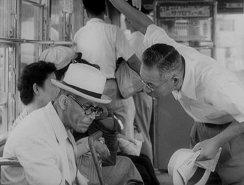 Movie still from “I Live in Fear” (1955), directed by Akira Kurosawa – A group of people sitting on a train; Medium shot, Over the shoulder angle