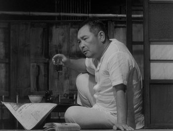 Movie still from “I Live in Fear” (1955), directed by Akira Kurosawa – A black and white photo of a man sitting on the ground; Medium shot, Low angle