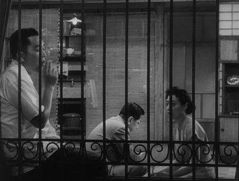 Movie still from “I Live in Fear” (1955), directed by Akira Kurosawa – Three people sitting in a jail cell; Medium shot, Low angle