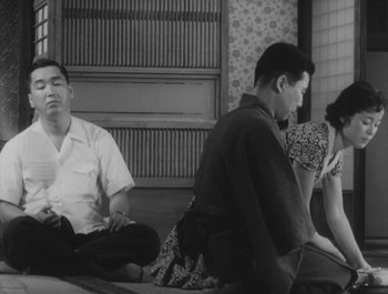 Movie still from “I Live in Fear” (1955), directed by Akira Kurosawa – A group of people sitting on the ground in front of a wall; Medium shot, Low angle