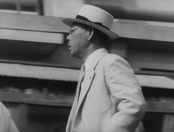 Movie still from “I Live in Fear” (1955), directed by Akira Kurosawa – A man in a suit and a hat walking down a street; Close Up shot, Low angle