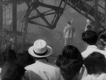 Movie still from “I Live in Fear” (1955), directed by Akira Kurosawa – A group of people standing in front of a building; Wide shot, High angle