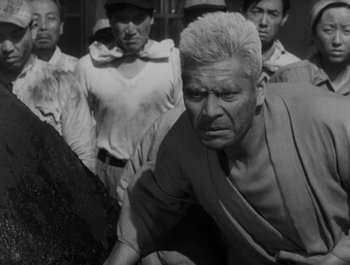 Movie still from “I Live in Fear” (1955), directed by Akira Kurosawa – An old man with a beard and a bunch of people; Medium shot, Low angle