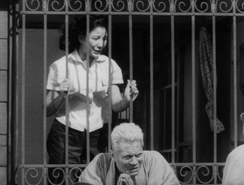 Movie still from “I Live in Fear” (1955), directed by Akira Kurosawa – An old man and a woman behind a fence; Medium shot, Low angle