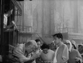 Movie still from “I Live in Fear” (1955), directed by Akira Kurosawa – An old photo of a group of people gathered around; Wide shot, High angle