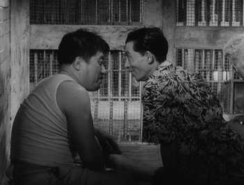 Movie still from “I Live in Fear” (1955), directed by Akira Kurosawa – Two young men talking to each other in front of a building; Medium shot, Low angle