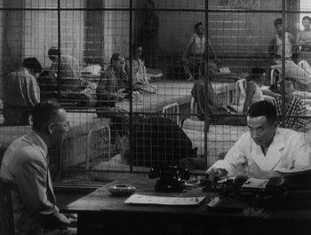 Movie still from “I Live in Fear” (1955), directed by Akira Kurosawa – A group of people sitting around a table; Wide shot, High angle
