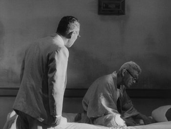 Movie still from “I Live in Fear” (1955), directed by Akira Kurosawa – Two men standing next to each other on a bed; Medium shot, Over the shoulder angle