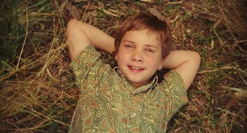 Movie still from “I Love You Phillip Morris” (2009), directed by John Requa – A boy laying in the grass with his hands behind his head; Close Up shot, Overhead angle